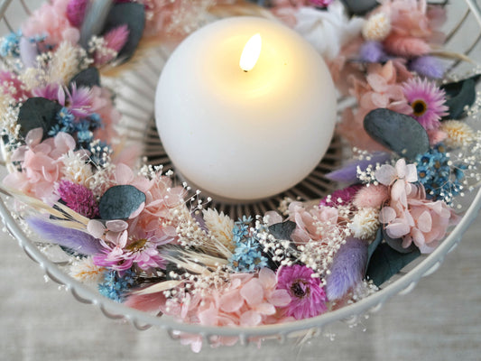Tischdekoration: handgefertigte Trockenblumenkranz mit zarten Blüten in rosa, eisblau, lila/flieder und weiß, ergänzt durch konservierten Eukalyptus und Schleierkraut