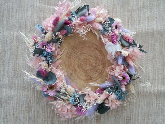 Tischdekoration: handgefertigte Trockenblumenkranz mit zarten Blüten in rosa, eisblau, lila/flieder und weiß, ergänzt durch konservierten Eukalyptus und Schleierkraut