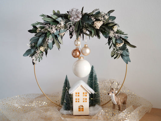 Weihnachtsdekoration Tischdekoration: Stehender Trockenblumenkranz gebunden an einen Metallring aus haltbaren Olivenzweigen, Eukalyptus und Tanne Thuja. Christbaumkugeln und Häuschen