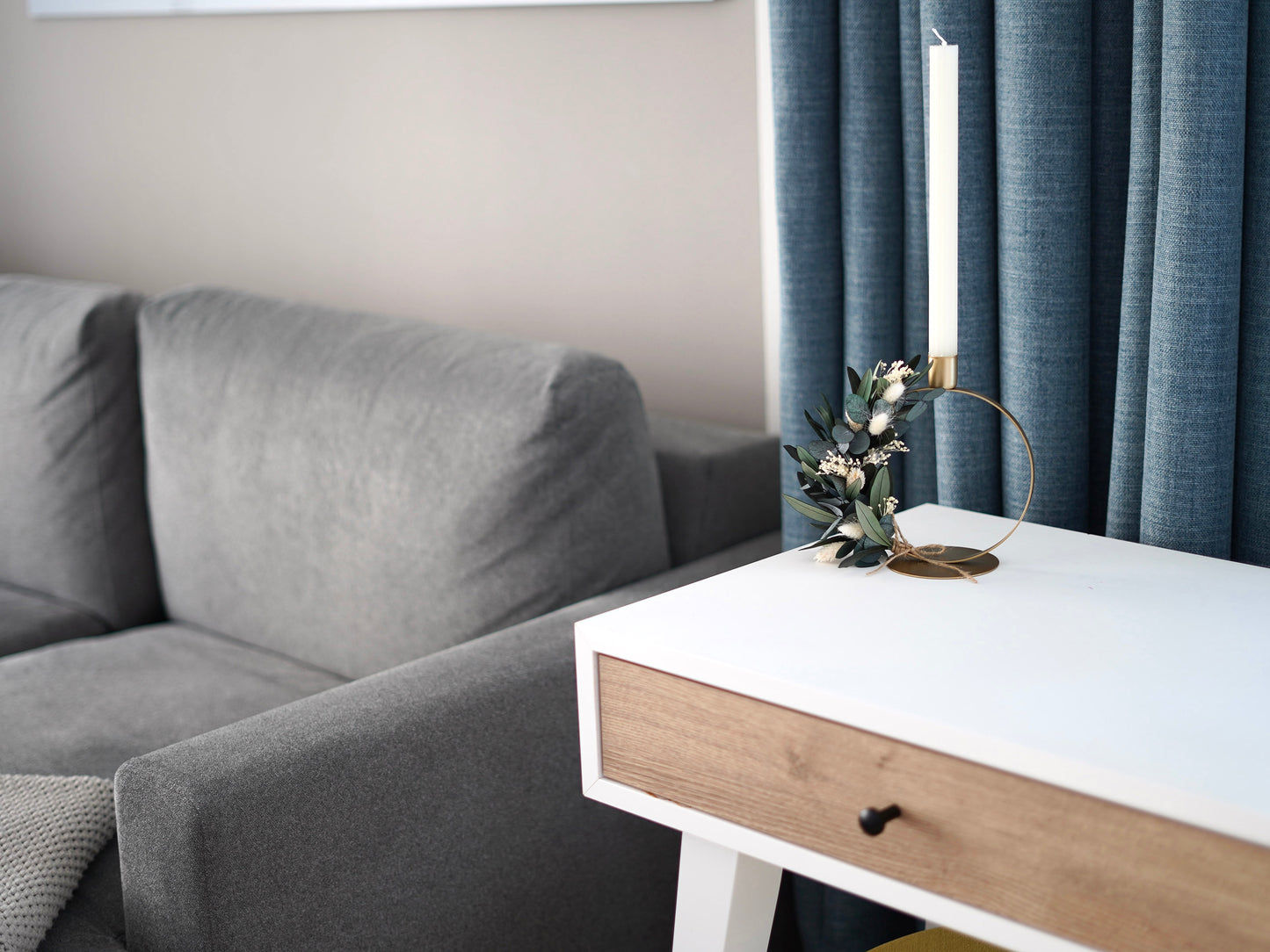 Goldener Kerzenhalter mit Eukalyptus, Olivenzweigen und Trockenblumen als moderne Boho-Tischdekoration in einem stilvollen Wohnraum.