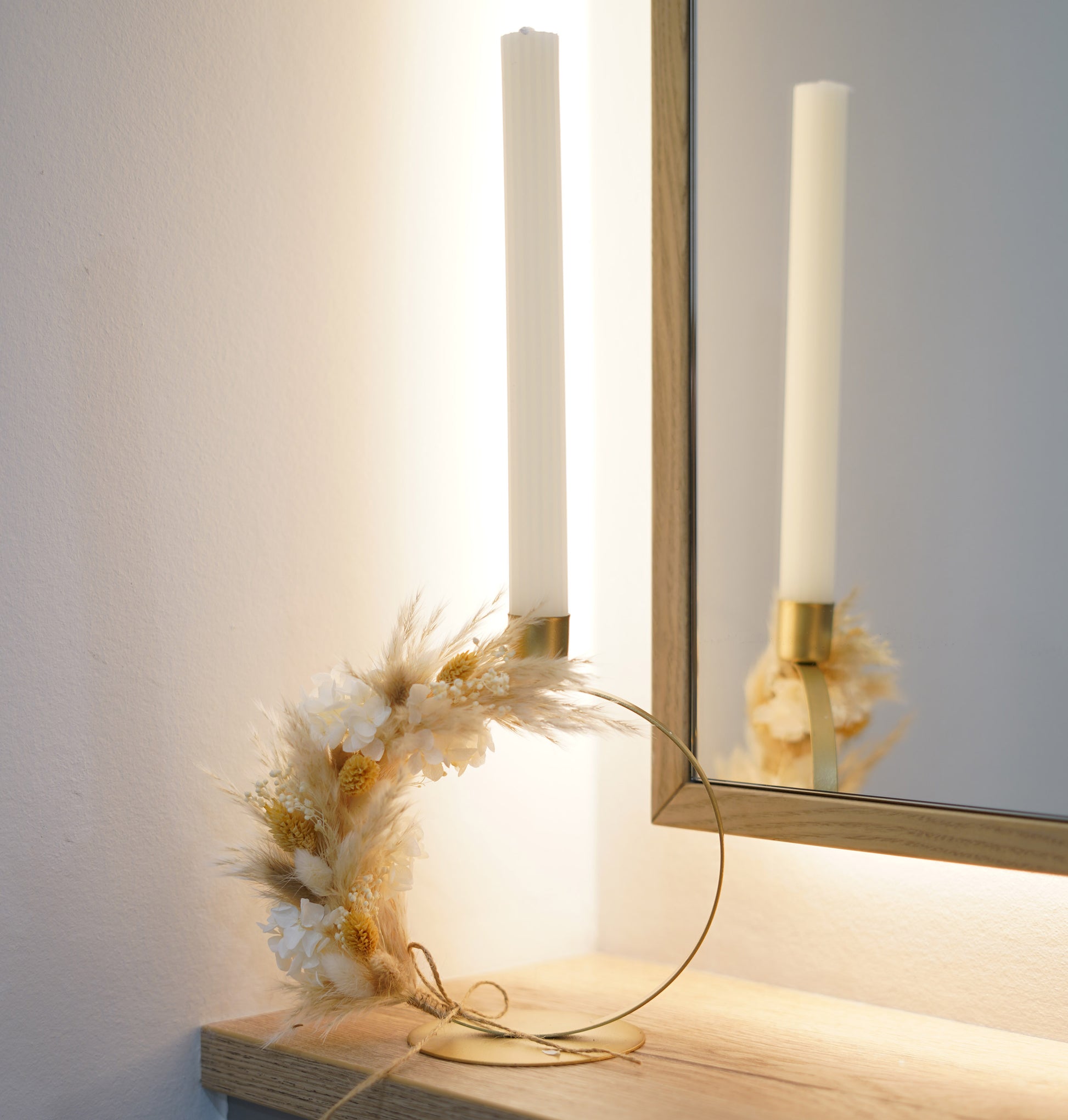 Detailaufnahme des goldenen Stabkerzenhalters mit Trockenblumen-Arrangement aus Pampasgras, Lagurus, Phalaris und Hortensie.