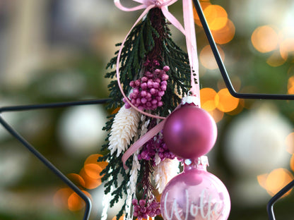 Detailansicht eines handgefertigten Metallsterns mit natürlichen Trockenblumen in grün und rosa
