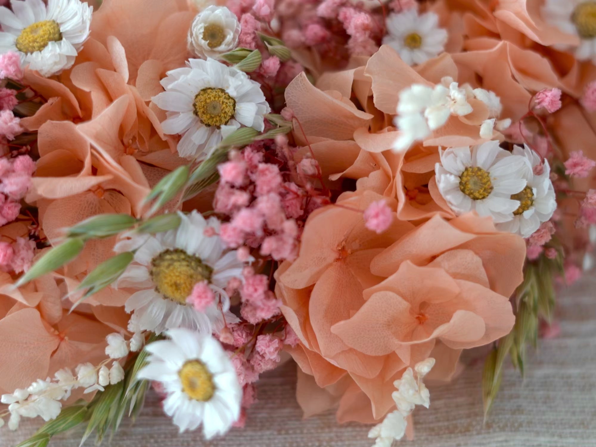 Video laden: Nahaufnahme eines handgemachten Trockenblumenkranzes mit pastellfarbenen Blüten und natürlichen Materialien